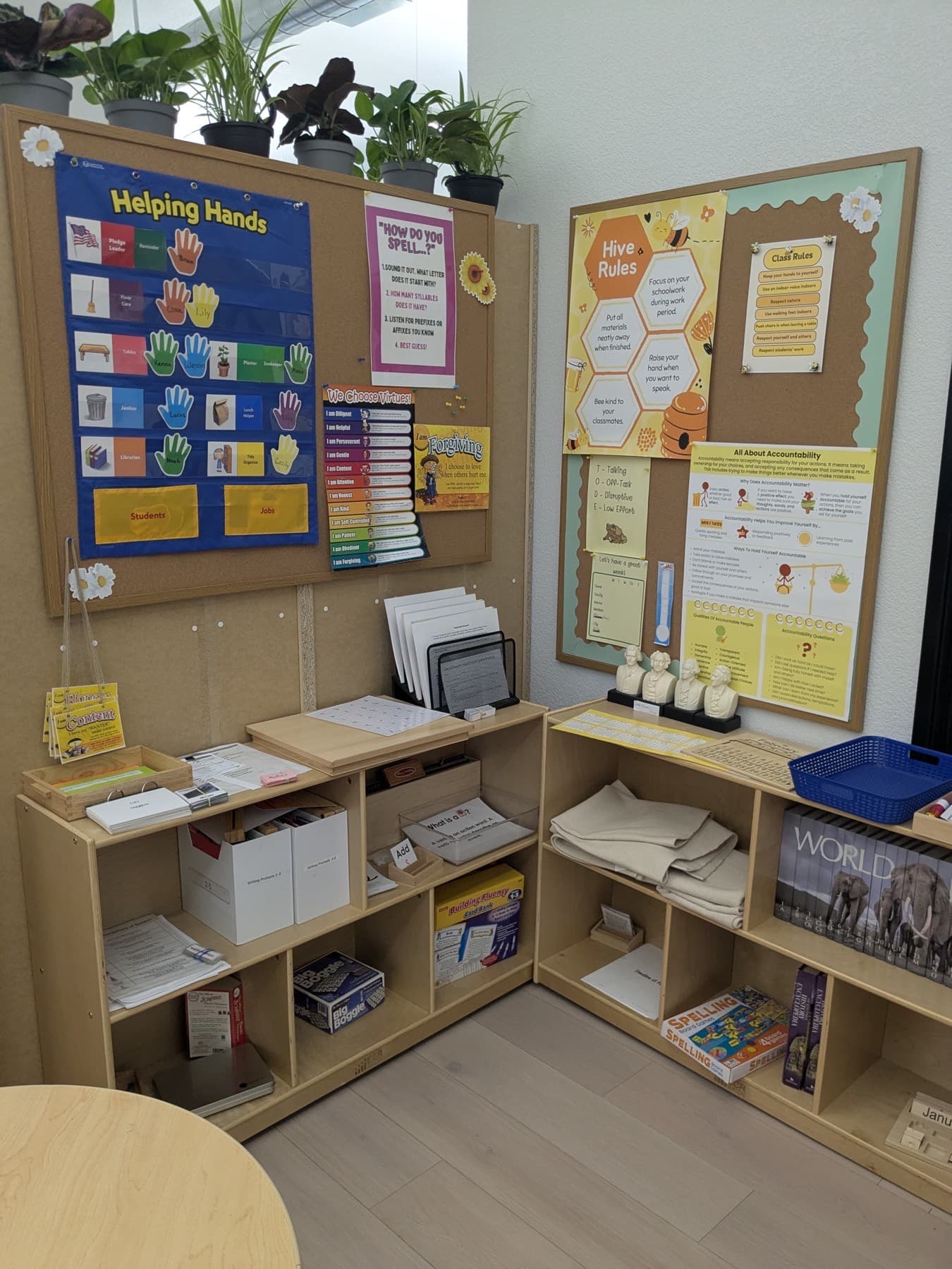 A Meadow View Learning classroom wall with a Helping Hands job chart, a virtue chart and the Hive Rules board above the materials shelves