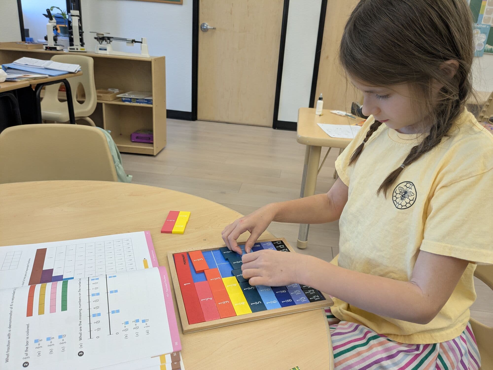 A student working with colored fraction bars and a fractions worksheet