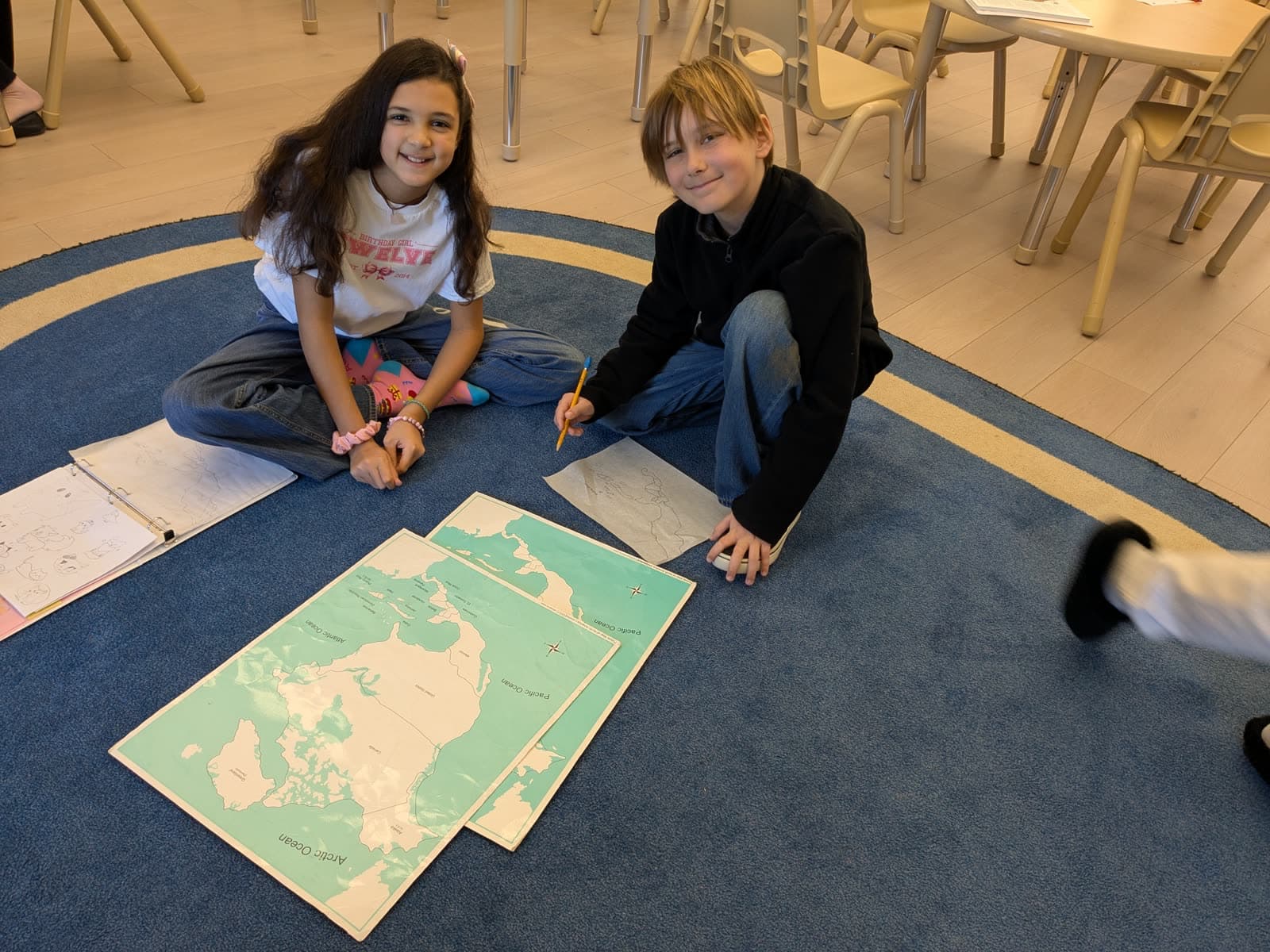 Two students working together on large floor maps in a Meadow View Learning classroom