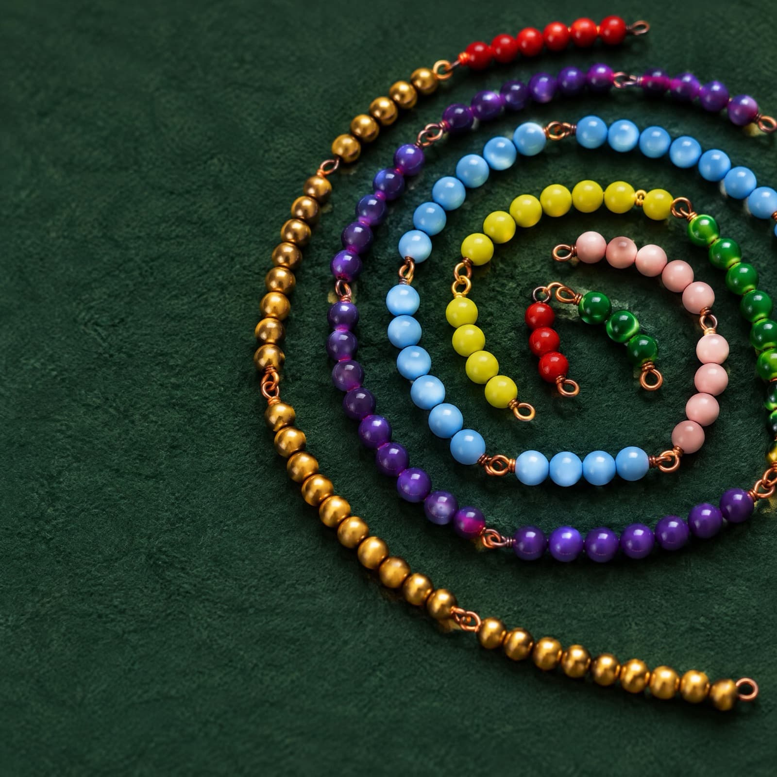 Montessori bead chains in bright colours laid out on green felt